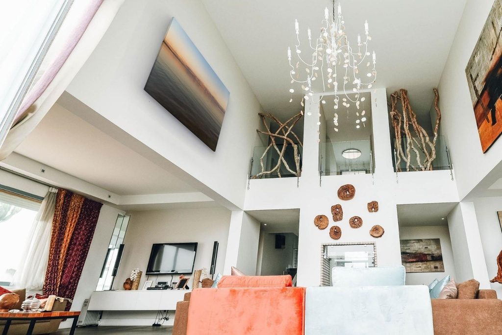 Bright white room in double-height, with angled walls, with art mocked up using ArtPlacer’s Personal Spaces.