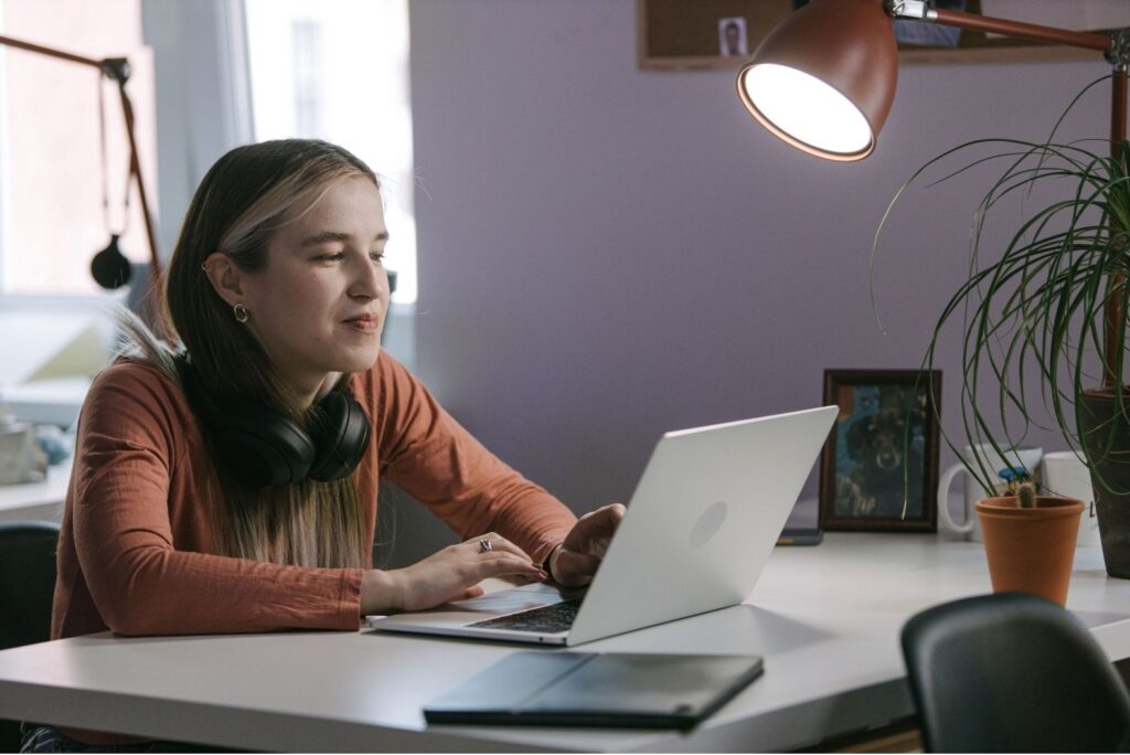 Woman sitting at a desk, working on her computer. She's preparing her application to artist opportunities 2026.