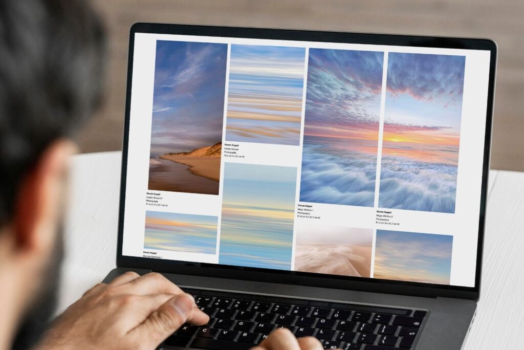 Person at a laptop browsing a curated grid of seascape and sky photographs with artwork details.